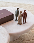 Three small figurines on a marble table next to a giftbox.