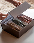 Person opening a box containing three small sculptures in different colors.