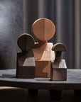 Three Gardeco Ceramic Sculpture The Muses Plus Clio Natural, with a natural finish, sit on a table next to a lamp.