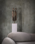 Decorative sculpture called Luxta from Gardeco on a pedestal in front of a textured wall with a gray sofa available at Spacio retail stores in India