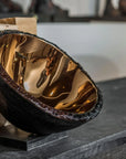 Gardeco Medium Bronze Luxury Decorative Tableware Bowl artistically placed near vintage books, capturing its reflective bronze interior and sophisticated glass texture, at Spacio India retail stores and online.