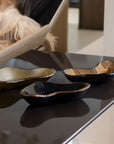 A set of Gardeco Ameba G bronze glass platters, including black top versions, displayed on a luxury coffee table – elegant tabletop accents at Spacio India