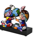 Colorful figurine of three characters holding hands on a black base