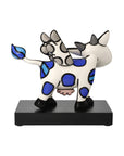 Back view of abstract sculpture of a cow with blue spots on a black base