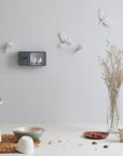 Haoshi Sparrow Clock in Dark Gray color on a grey wall with table ware accessories beside a vase available at Spacio india for modern and luxury interiors from our Timepieces and clocks collection.