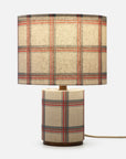 A table lamp with a cylindrical base and matching drum shade, both covered in a beige plaid fabric pattern with red, blue, and green stripes, shown against a light gray background.
