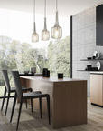 Modern kitchen with wooden island, black chairs, and pendant lights.