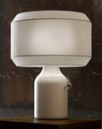 Table lamp with a white shade and base on a dark marble surface