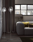 Modern living room with two glass floor lamps and a gray sofa.