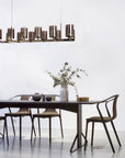 Dining area with a modern chandelier, table, and chairs against a white wall.