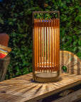Wooden solar lantern on a wooden table with a green leafy background by Les Jardins available at Spacio retail stores in Mumbai & Kolkata.