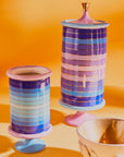 Jonathan Adler Scala stripe Vanister Tall Vase on a orange surface with bowl available at Spacio India for Luxury Home Decor Accessories collection.