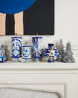 Jonathan Adler Druggist Eye Vase displayed on a white fireplace mantle with silver Christmas trees - eye-catching art piece available at Spacio India.