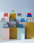 Multiple lacquer box designs including Jonathan Adler Large Lacquer Botanist Box arranged on pastel pedestals – Spacio India display.