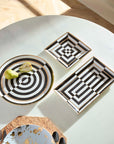 Jonathan Adler designer trays with circular and square geometric art motifs arranged on a dining table – part of the signature Op Art collection at Spacio India.