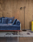 Blue velvet sofa in a room with wooden walls and colorful vases.