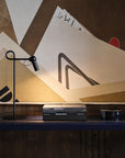 Modern black floor lamp on a wooden floor with abstract art in the background