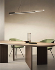 A modern dining room with a wooden table and chairs, featuring the KDLN Dala Linear Home Office Desk Ceiling Light for a harmonious synthesis of form and function.