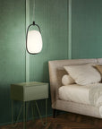 Modern bedroom with green textured wall, bed, and side table.