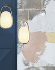 Two pendant lights hanging against a textured wall with peeling paint.