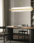 A modern office with a wooden desk, bookshelves, and a KDLN Nami Suspensesion Home Office Desk Ceiling Light diffuser.