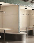 A dining room with adjustable tables and dimmable chairs in the middle of the room, illuminated by a KDLN Poise Ceiling Lamp.