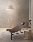 Modern lounge chair in a minimalistic room with a floor lamp and wooden side table.