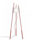 Floor lamp with red wooden legs and a white lampshade on a white background