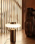 KDLN Tratto Table Lamp in black finish styled on a floor next to a floor sculpture. Available at Spacio retail stores in India.