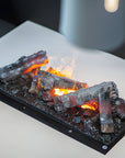 Artificial fireplace log set on a white surface with a blurred background available at Spacio retail stores in Mumbai & Kolkata.