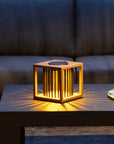 Wooden solar table lamp on a coffee table with a glass of wine in a dimly lit room.