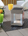 Outdoor table setting with a metal solar lantern, colorful glasses, and lemons on a wooden table.