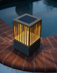 Solar-powered outdoor light on a brick ledge by a pool