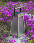 Le Jardins Solar lantern on a stone path surrounded by purple flowers