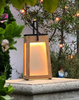 Wooden solar lantern with warm glow in a garden setting by Les Jardins available at Spacio retail stores in Mumbai & Kolkata.