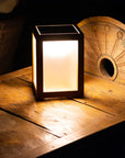 Small illuminated solar table lamp on a wooden surface with a dark background by Les Jardins available at Spacio retail stores in Mumbai & Kolkata.