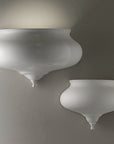 Two white wall sconces on a gray wall in ceramic by Lorenzon available at Spacio in India.