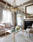 Luxurious living room with a crystal chandelier, sofa, coffee table, and decorative mirror.