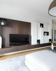 Modern living room with wooden entertainment console, TV, and decorative items.