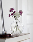 Maleras Crystal Into The Woods Vase with a pink flower on a console table with other accessories in modern interiors available at Spacio India from Decor Accessories Collection of Vases.