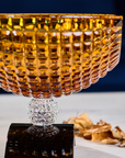 Closer Side look of Mario Cioni Crystal Amber Bowl with Black base on a a wooden table available at Spacio India for luxury home decor accessories collection of Bowls & Centerpieces.