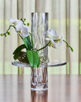 Clear Crystal vase with white orchids on a wooden surface