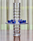 Decorative crystal vase with blue candles on a wooden surface