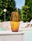 Orange crystal vase with a textured surface on the ledge of pool side