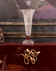 Decorative crystal vase on a reflective surface with a textured wall in the background