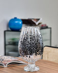 Decorative crystal vase with black speckles on a wooden table with a blurred background