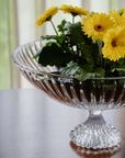 Clear crystal bowl with yellow flowers on a neutral background