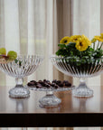 Clear crystal bowls with flowers and chocolates on a table against a curtain background