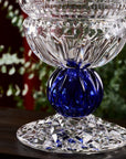 Close up of decorative crystal vase with blue and clear design on a dark surface