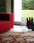 Red sofa in a living room with colourful crystal vases on the floor.
